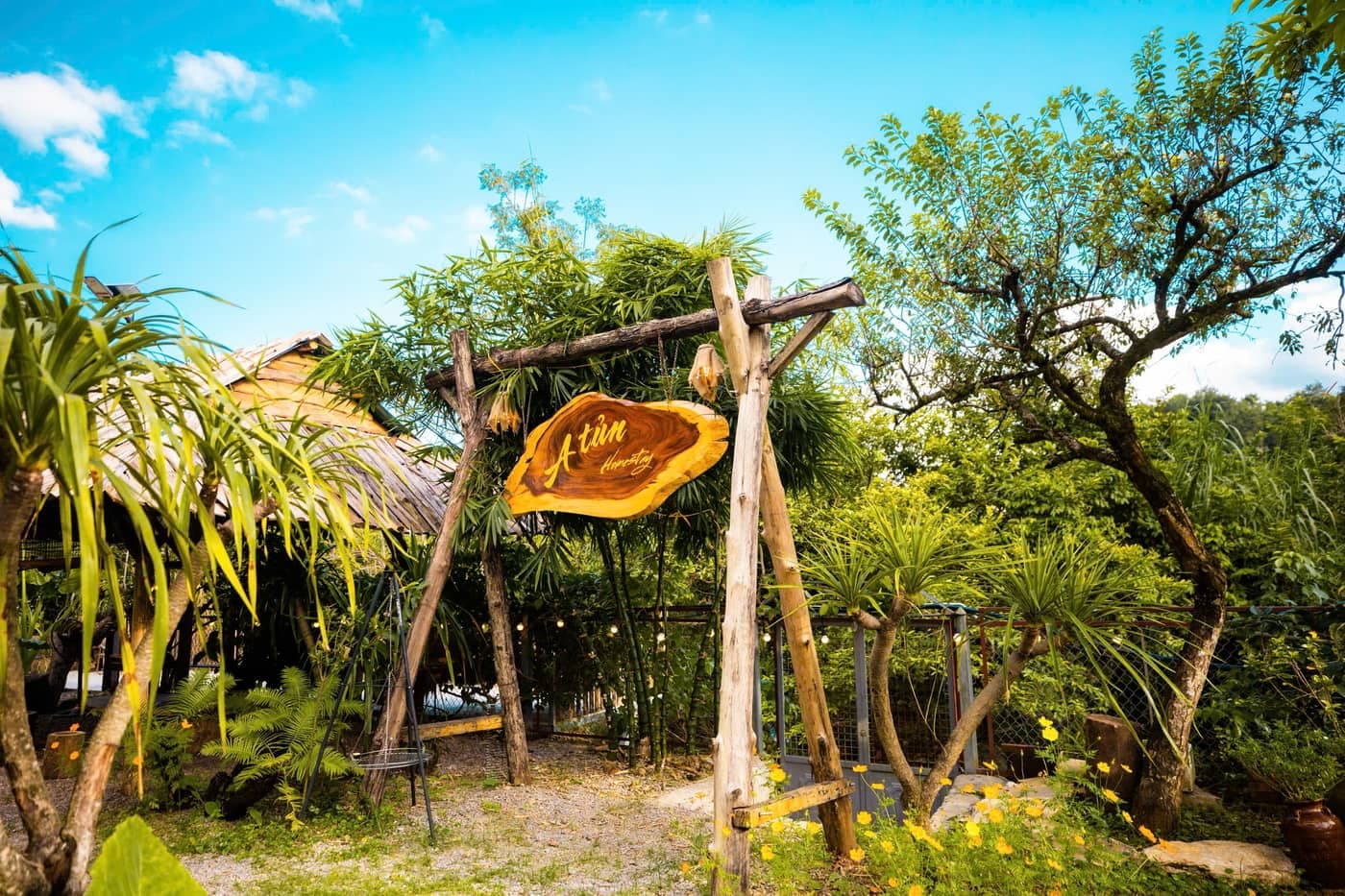Ngoại cảnh A Tủn Homestay: nhà gỗ hai tầng, biển hiệu gỗ, sân đỗ xe (3/4)